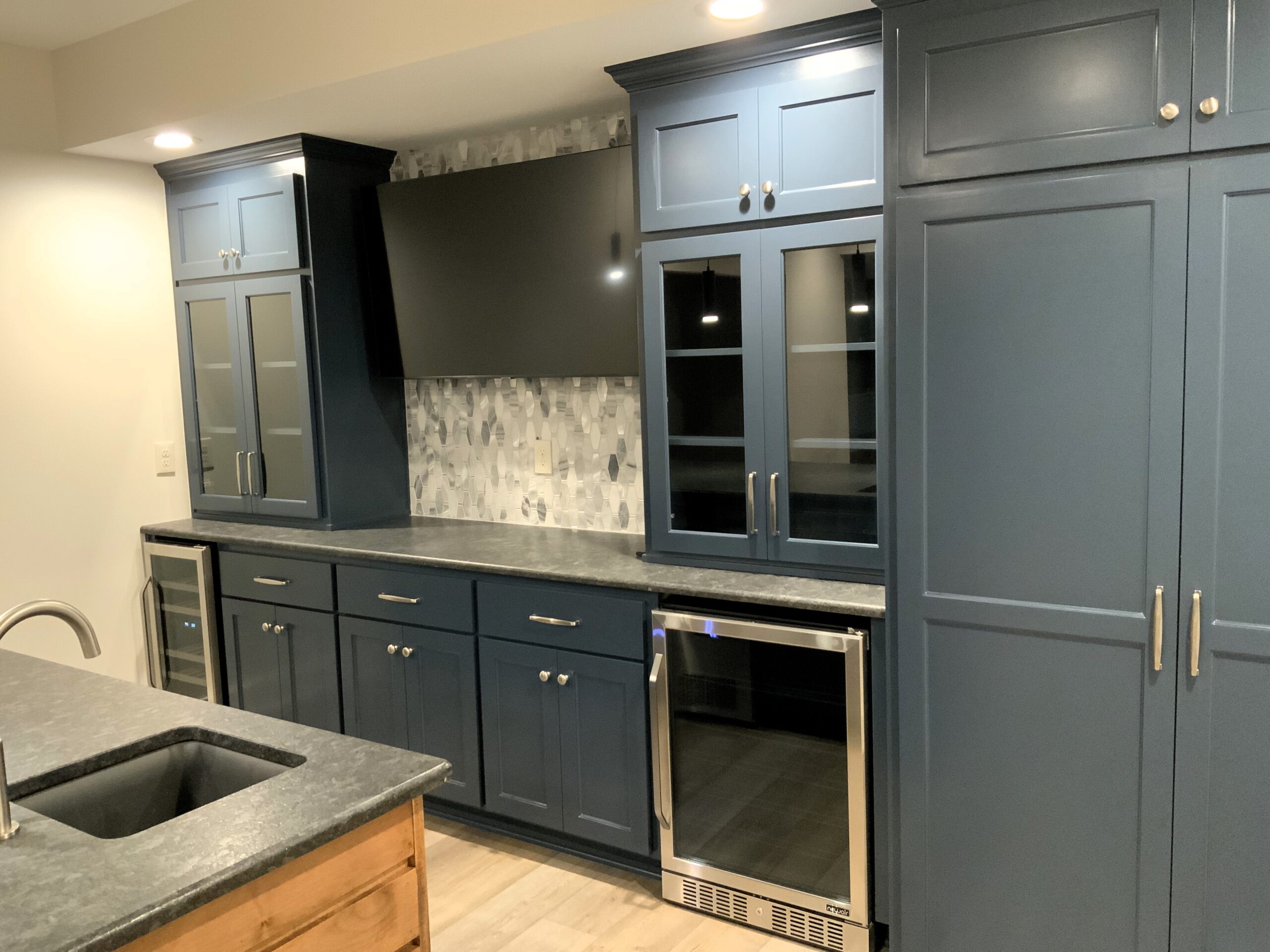 Modern Kitchen Design Featuring Navy Blue Cabinets, Granite Countertops, and a Sleek Built-in Beverage Fridge, Showcasing Stylish Storage and Functionality.